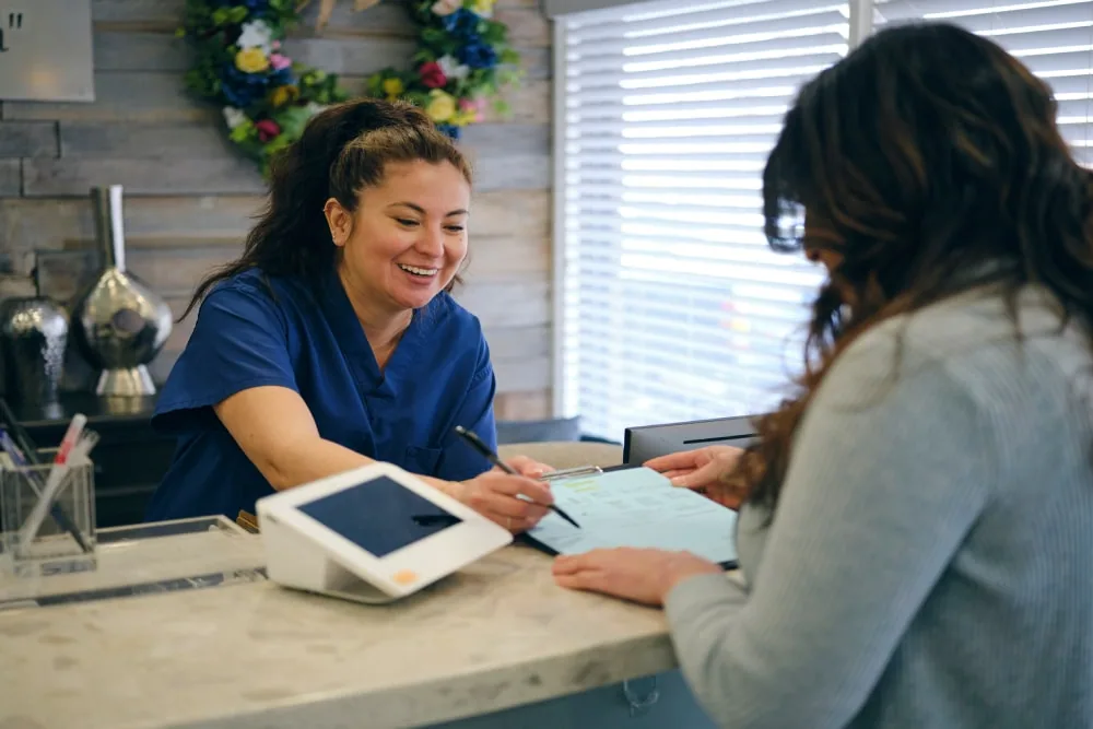 Dermatology clinic front desk staff assisting patient with check in and payment